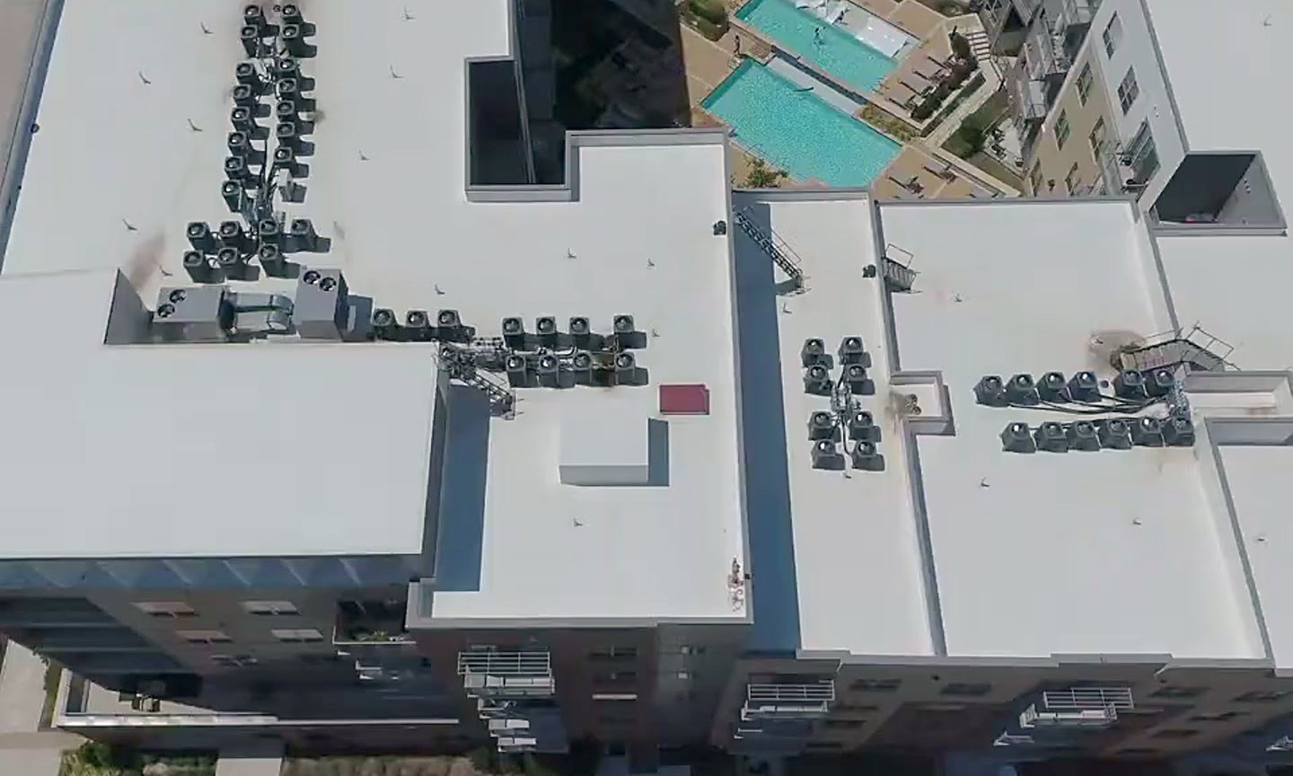 An apartment rooftop pool deck and the white roof around it at Alta Palisades